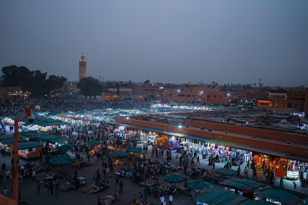 Aerial view o6 days Tour in Morocco Marrakech to Fesf lively evening marketplace in Marrakech, filled with people and vibrant stalls.